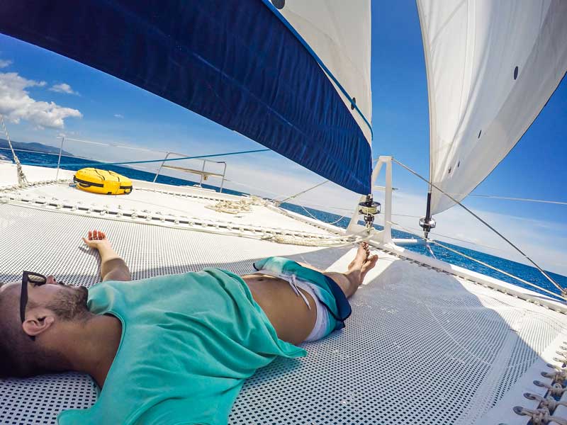 Relaxing on the net of a catamaran while hopping the Greek Cyclades