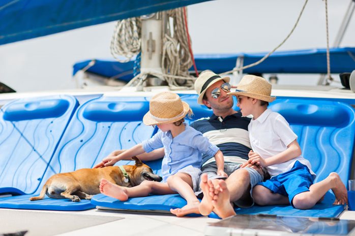 Father, his sons and a dog on a sailing boat deck